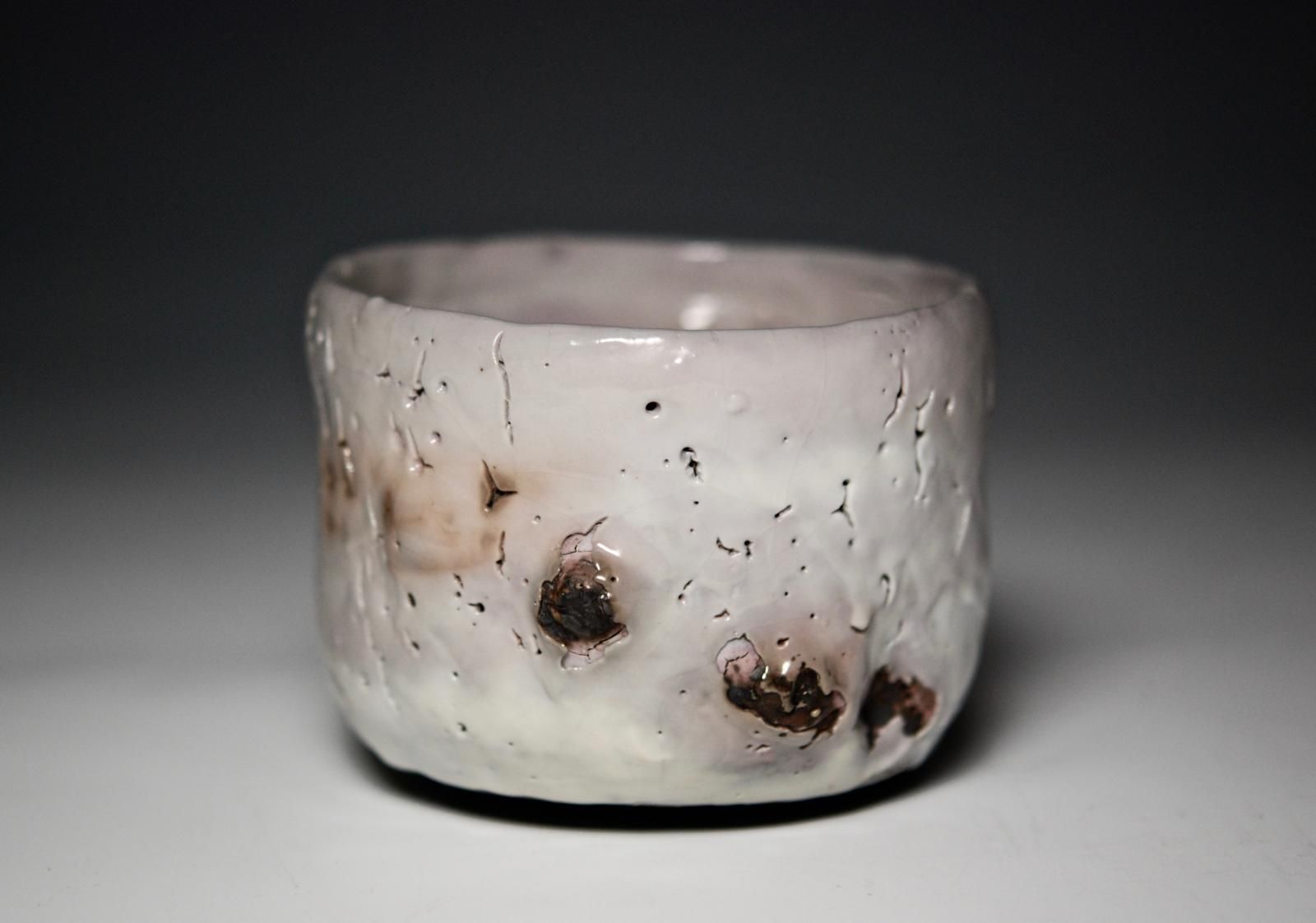 Thrown and altered Chawan, using black stoneware and white shino glaze.  Fired in a reduction atmosphere in an oil fired kiln. by Margaret Curtis